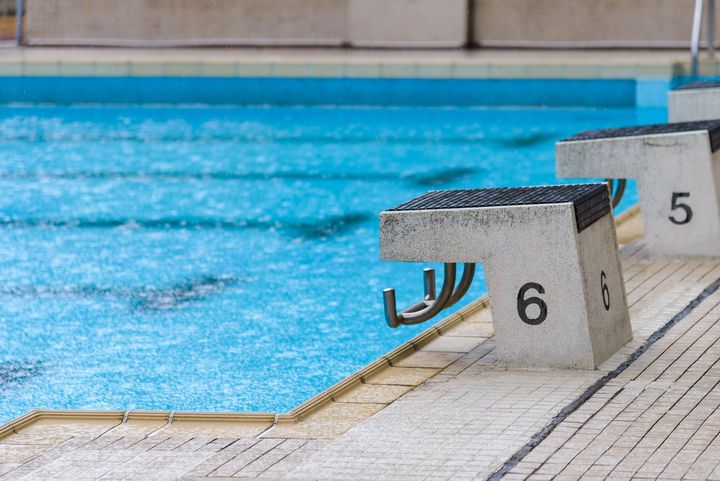 empty diving block stands with numbers in outdoor swimming pool on rainy day